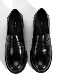 Zwart gelakt leren loafers met een gladde afwerking, ronde neus, verhoogde naaddetails en leren binnenzool. Kenmerkt zich door een band over de wreef.