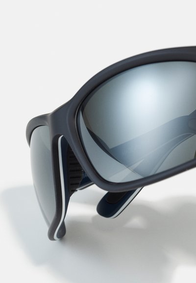 Occhiali da sole con montatura opaca scura, lenti grigie specchiate e dettagli bianchi. Fianchi flessibili e impugnature testurizzate per il comfort.