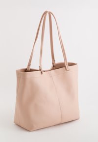 Bolso tote de piel rosa con textura suave, dos asas largas y un diseño sin costuras que presenta sutiles detalles de costura y una forma estructurada.