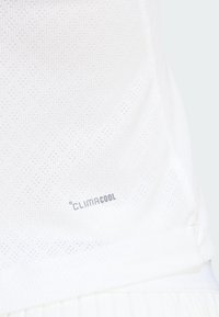 Camiseta de rendimiento blanca con un patrón texturizado, que presenta el logo "CLIMACOOL" en gris. La tela es ligera y transpirable.