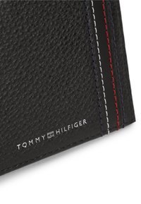 Γωνία πορτοφολιού από μαύρο δερματό υφή με λευκή, κόκκινη και μπλε ραφή και ασημένιο λογότυπο Tommy Hilfiger.