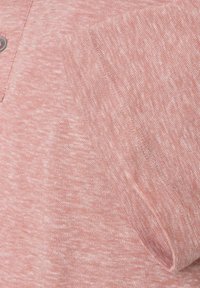 Jasnoróżowy sweter z textured wzorem dzianiny, z zapięciem na guziki oraz kieszenią na piersi, z subtelnym ukośnym przeszyciem.