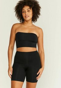 Svart avtagbar crop top i stretchigt material, kombinerad med högmidjade svarta shorts. Slät textur, minimalistisk design.