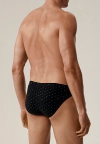 Czarne kąpielówki z drobnym niebiesko-białym wzorem w kropki. Wykonane z elastycznego materiału, zaprojektowane, aby ściśle przylegać z schludnym wykończeniem.