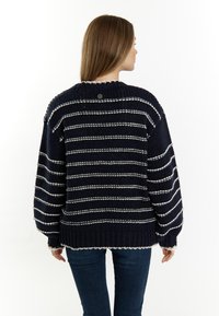 Maglione in maglia con righe orizzontali blu navy e bianche, orlo e polsini a coste, e scollatura rotonda. Presenta un piccolo logo sulla parte posteriore del collo.