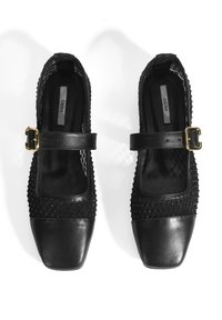 Chaussures noires avec un embout carré, en cuir, avec des détails en textile tissé et une sangle à boucle dorée sur le cou-de-pied.