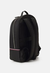 Zaino nero con una texture liscia, dotato di una zip argentata, schienale in rete e una striscia colorata alla base. Design elegante ed ergonomico.