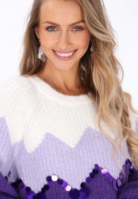 Pulover tricotat purpuriu și alb, cu un model în zigzag, având accente de paiete pe tiv și o finisare texturată și confortabilă.