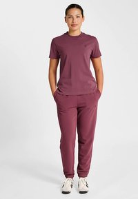 Athletisk outfit i bærfarver med kortærmet top og tilspidsede bukser. Fremstillet i let vævet stof med elastiske manchetter og et diskret logo.