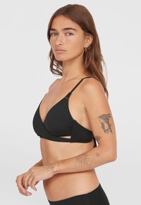 Svart triangelformad bikiniöverdel med utklippningsdesign, justerbara tunna remmar, rynkdetalj och mjuk tygkvalitet. Inga mönster eller accenter.