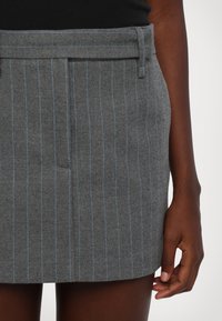 Jupe en laine grise avec des rayures тонales bleu clair, dotée d'une taille et de poches latérales ; finition texturée et coupe ajustée.