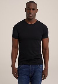 Zwarte, kortom mouw t-shirt gemaakt van soepel materiaal. Strak ontwerp met een ronde halslijn; gecombineerd met blauwe denim jeans.