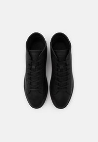 Czarne wysokie trampki ze skóry o gładkiej fakturze, z zaokrąglonym noskiem i płaskimi sznurowadłami. Na języku znajduje się logo, a na bokach szczegóły przeszyć.