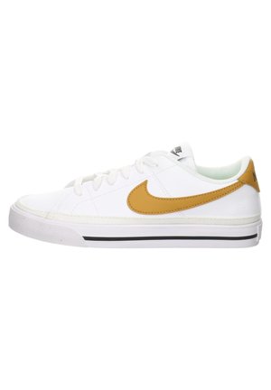 Baskets basses blanches avec le swoosh Nike jaune moutarde, fermeture à lacets, et bande noire sur semelle blanche en caoutchouc, vue de profil.