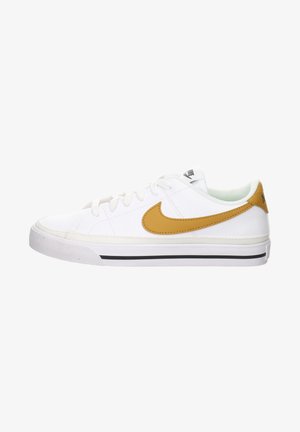 Baskets basses blanches avec le swoosh Nike jaune moutarde, fermeture à lacets, et bande noire sur semelle blanche en caoutchouc, vue de profil.