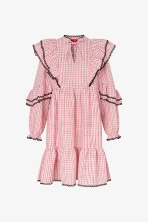 Ροζ φόρεμα με καρό μοτίβο, μαύρη δαντέλα στο τελείωμα, βολάν στους ώμους, μακριά φουσκωτά μανίκια, λαιμόκοψη με άνοιγμα και κορδόνι, και στρωτή ποδόγυρος.