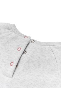 Primer plano de una tela de color gris claro con cierres de botones a presión y ojales de botón cosidos en rosa en el borde de un collar acanalado.