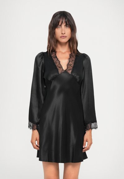 Crna satenska haljina s dugim rukavima, čipkastim detaljima na izrezu i manžetama, te opuštenim krojem, prikazujući glatku teksturu i elegantan dizajn.