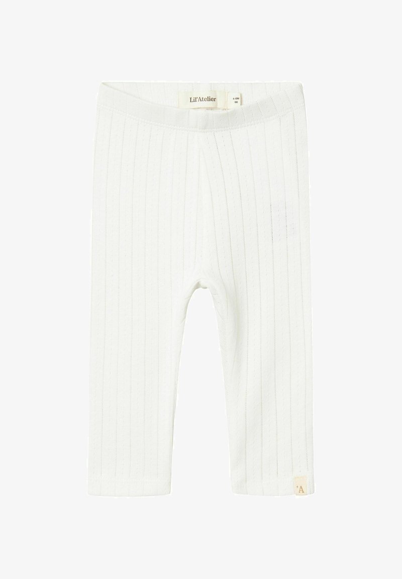 Leggings blancs côtelés en matériau doux, dotés d'une taille plate et d'une petite étiquette de marque au bord.