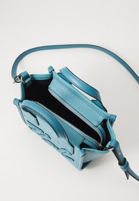 Small blue leather handbag with structured design, dual zipper compartments, and textured surface. Features top handles and an adjustable strap.
