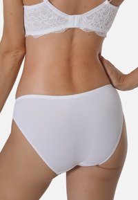 Weißer Baumwollslip mit glatter Textur, hoher Taillenschnitt und elastischem Bund. Spitzenakzent auf der Rückseite des passenden BHs sichtbar.