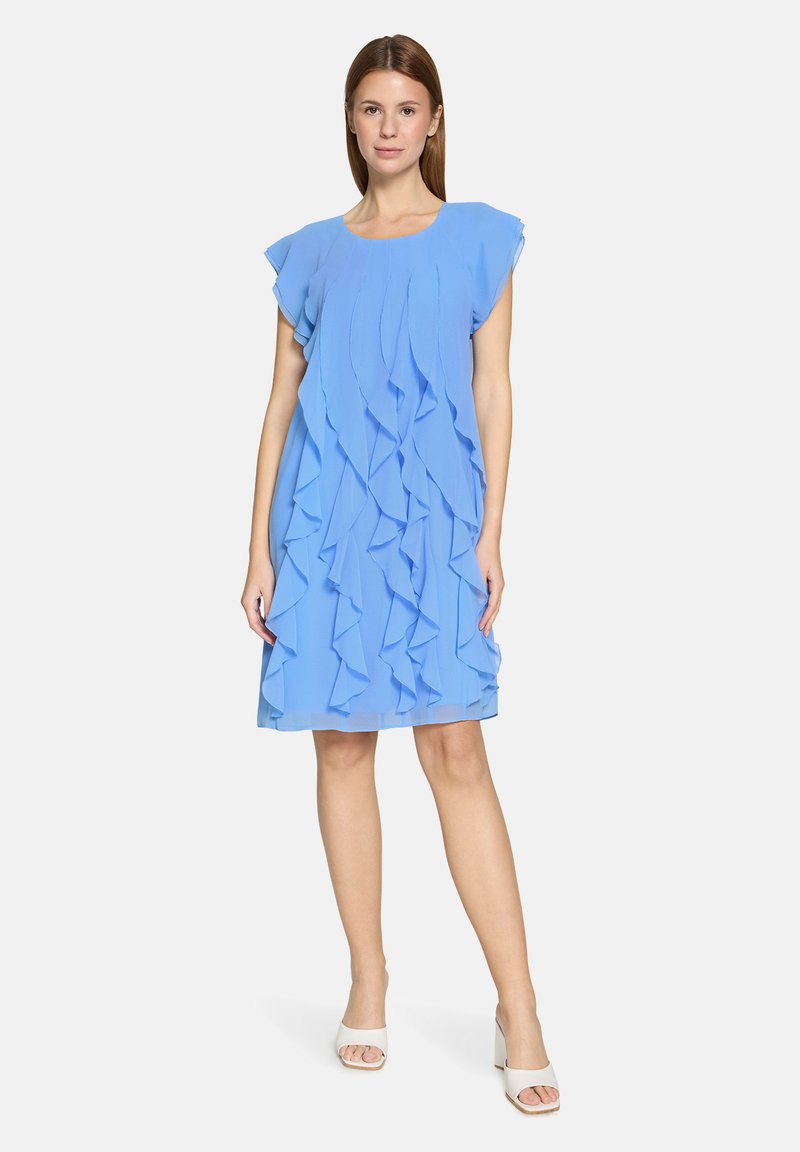 Robe bleu clair avec volants superposés, manches courtes et coupe ample. Tissu lisse et léger, longueur au genou, avec des accents minimalistes.