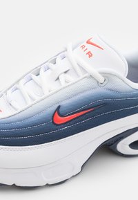 Nike Air sportbačiai su gradientiniu dizainu mėlynos ir baltos spalvų, raudoni akcentai, tekstūruotas viršus ir paminkštintas padas komfortui.
