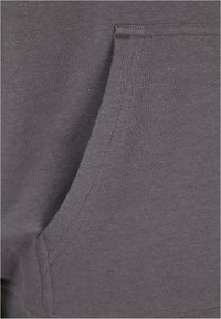Tessuto di cotone grigio con una tasca laterale e dettagli di cucitura. La trama è liscia e il design è semplice e funzionale.