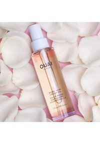 Klar glassprayflaske som inneholder rosehår- og kroppsolje. Har et hvitt plastpumpehette, med rosa væske, omgitt av hvite rosenblader.