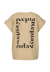 Beige oversized t-shirt met opvallende zwarte tekst in een herhalend vierkant patroon met de tekst "Replay." Eenvoudig en modern ontwerp.