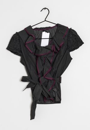 Haut cache-cœur noir avec manches courtes bouffantes ornées de pois blancs, bordure violette contrastante et volant à l'avant. Comprend un détail de lien en tissu.