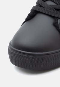 Must musta kingade ümmargune varvas, tekstuuriga kummist tald ja lame pael, esitleb sujuvat viimistlust ja minimaliseeritud disaini.