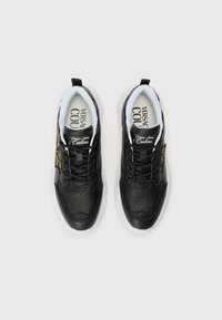 Baskets en cuir noir avec des détails perforés, semelle blanche et accents dorés contrastants. Présente des lacets noirs et des semelles intérieures de marque.