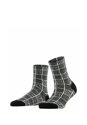 Een paar zwart-witte sokken met een boord, voorzien van een rasterpatroon met golvende lijnen en effen zwarte teen- en hielstukken.