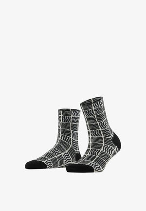 Een paar zwart-witte sokken met een boord, voorzien van een rasterpatroon met golvende lijnen en effen zwarte teen- en hielstukken.