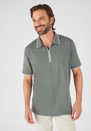 Polo in tessuto verde tenue, con mezza zip, colletto bianco a contrasto e dettagli in rete sulle maniche.