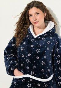 Coperta con cappuccio blu navy con motivo a stelle, realizzata in morbido tessuto peluche. Fodera in pile bianco attorno al colletto e alle tasche per un comfort aggiuntivo.