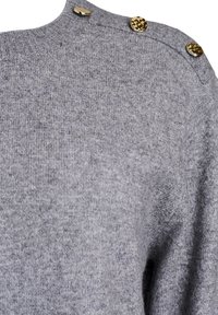 Pull en maille grise avec un col rond et trois accents de boutons dorés sur l'épaule. Texture douce avec une coupe légèrement décontractée.