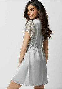Rochie din satin argintiu cu mâneci scurte din dantelă, talie strânsă, fustă fluidă și textură netedă. Prezintă detalii delicate din dantelă pe umeri.