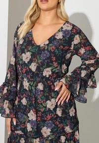 Vestido floral con base negra y flores en tonos rosa y púrpura, mangas largas acampanadas, escote en V profundo y cintura ceñida. Tela semitransparente.