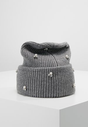 Bonnet tricoté gris décoré de petits clusters de perles et de strass, présenté sur un socle blanc sur un fond gris uni.