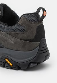 Schwarzer und grauer Wanderschuh mit einem Obermaterial aus Wildleder und Mesh, Vibram-Laufsohle, gepolstertem Kragen und einem Zugband hinten für ein einfaches Anziehen.