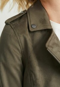Veste en suède synthétique vert olive avec fermeture éclair, accents de boutons-pression et design de col classique. Texture douce avec une finition mate.