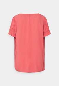 Blusa de manga corta en color coral, con cuello redondo, mangas abullonadas texturizadas y dobladillo curvado. Tejido suave con un brillo sutil.