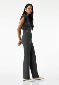 Grijze geribbelde gebreide top met korte mouwen, gecombineerd met bijpassende high-waisted flared pants en crèmekleurige flats, wat een gestroomlijnde silhouet creëert.