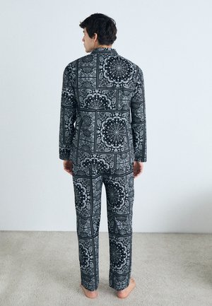 Black and white patterned pajama set featuring intricate designs, long sleeves, and pants with a relaxed fit, shown from the back.