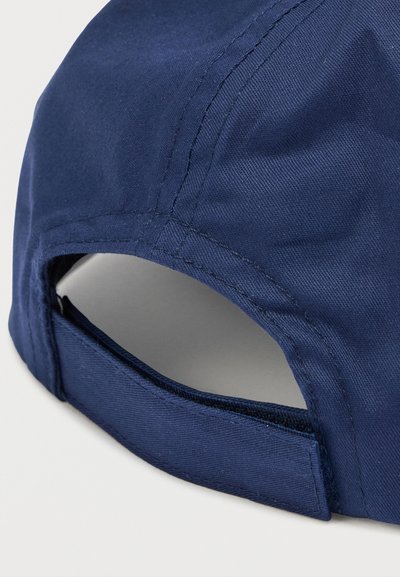Καπέλο σκούρου μπλε ναυτικού, κατασκευασμένο από λείο ύφασμα, με κυρτό γείσο και ρυθμιζόμενο λουράκι στο πίσω μέρος για σίγουρη εφαρμογή. Ορατή λεπτομέρεια ραφής.