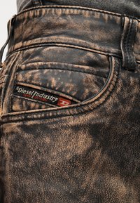 Μαύρο τζιν από denim με φθαρμένο, υφασμάτινο μοτίβο. Διαθέτει τσέπη με κολάζ και ετικέτα λογότυπου Diesel Industry. Μεταλλικές ραφές για διακοσμητικό αποτέλεσμα.