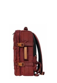 Zaino color marrone scuro con scomparto principale con zip, fibbie beige, spallacci imbottiti in rete e design rettangolare elegante. Tessuto testurizzato e spallacci regolabili.