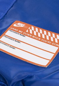 Mėlynas nailono audinio pleistras su oranžine etikete. Etiketei pridedami iš anksto spausdinti laukai vardams, su tekstu "PASIDALINK, KAI PABAIGSI".